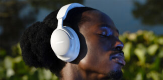Man wearing white Bose QuietComfort Ultra headphones outside.
