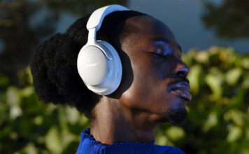 Man wearing white Bose QuietComfort Ultra headphones outside.