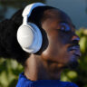 Man wearing white Bose QuietComfort Ultra headphones outside.