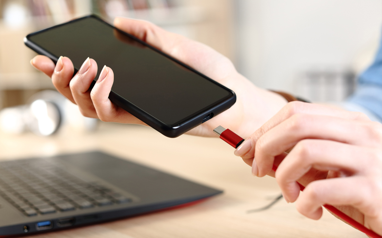 Person plugging in smartphone to charge via USB-C.