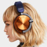 Blonde woman wearing Dyson OnTrac headphones in nickel and purple.