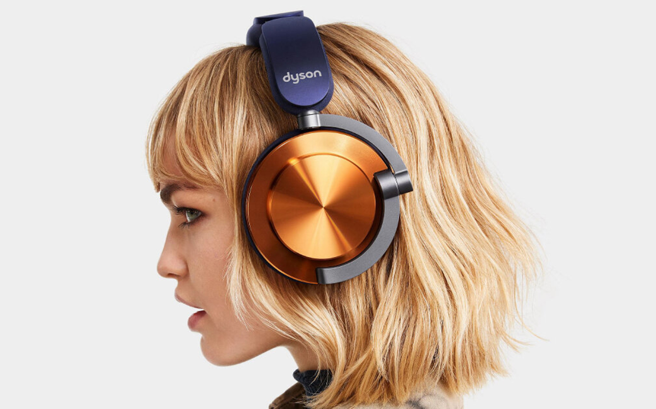 Blonde woman wearing Dyson OnTrac headphones in nickel and purple.