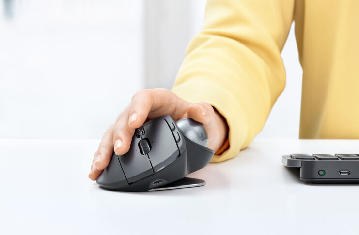 Person using Logitech MX Ergo mouse and trackball on desk.