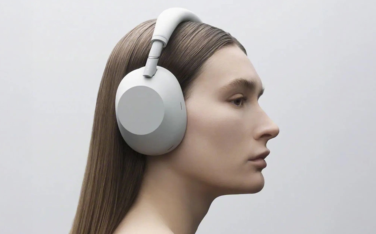 Brunette woman wearing Sony WH-1000XM6 headphones in grey.