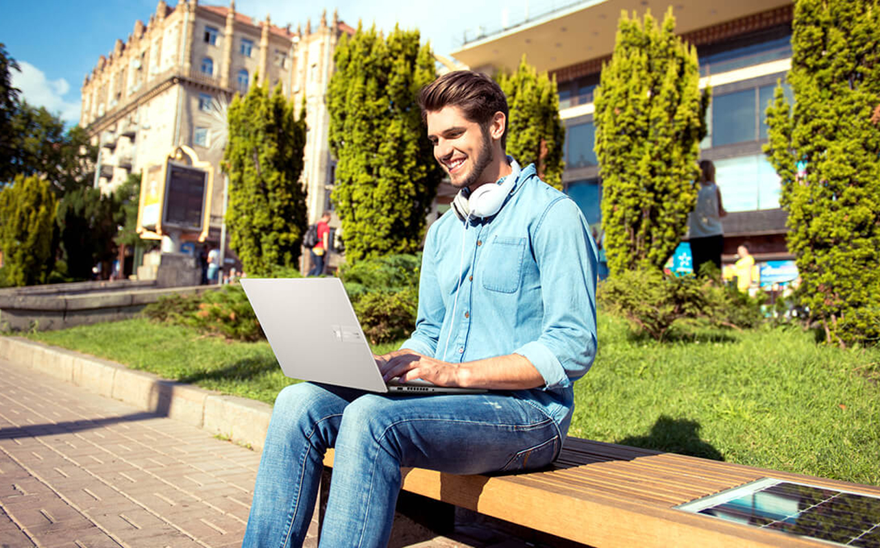 University student using laptop outdoors on campus.