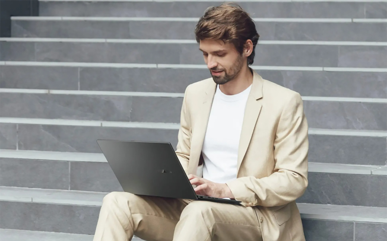 A man sitting on steps outside with an Asus Zenbook 14.