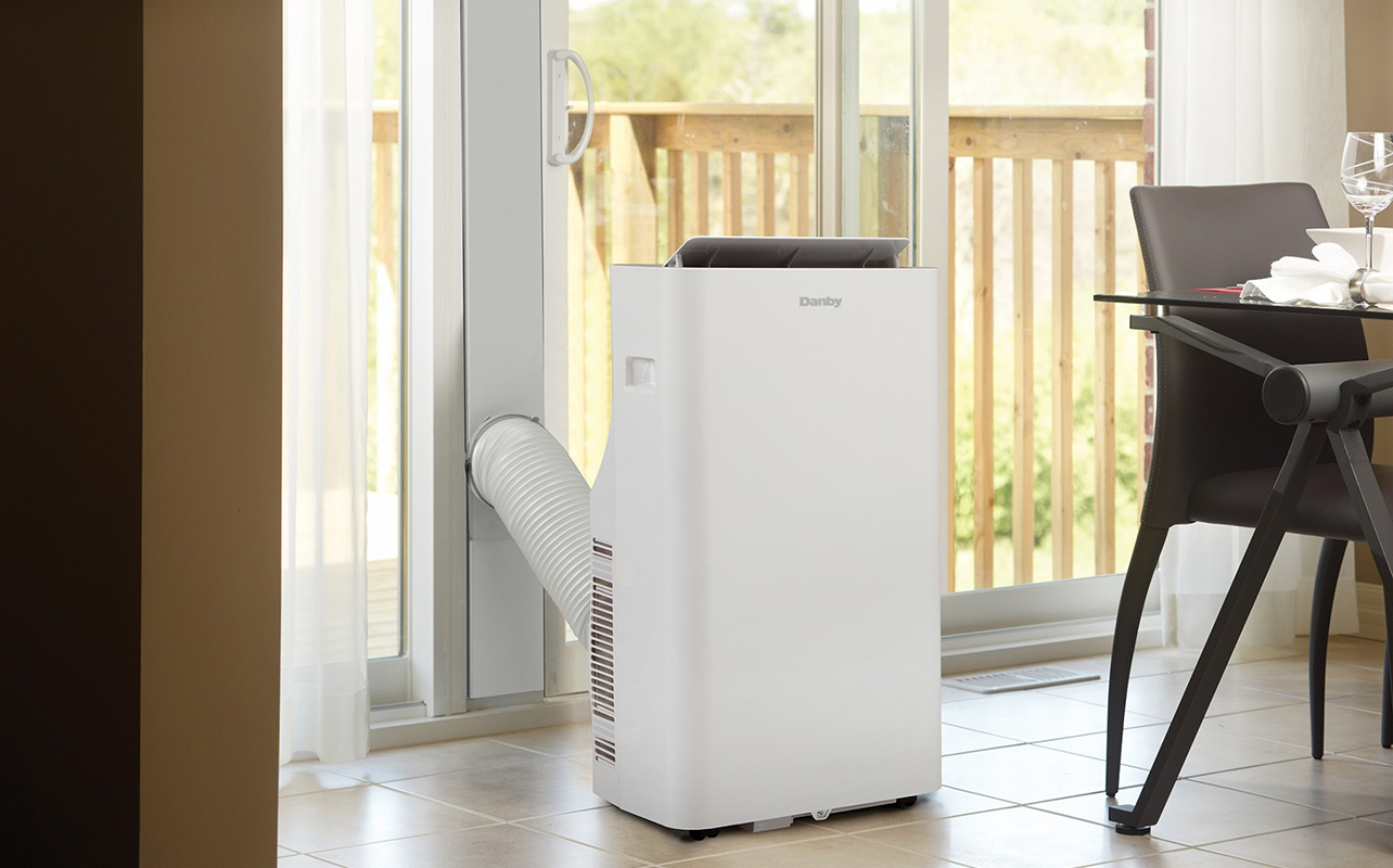 A Danby portable air conditioner by a large window.