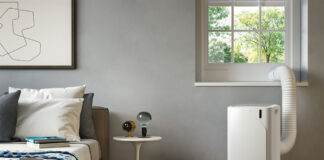 A De'Longhi portable air conditioner being vented out of a window in a bedroom.
