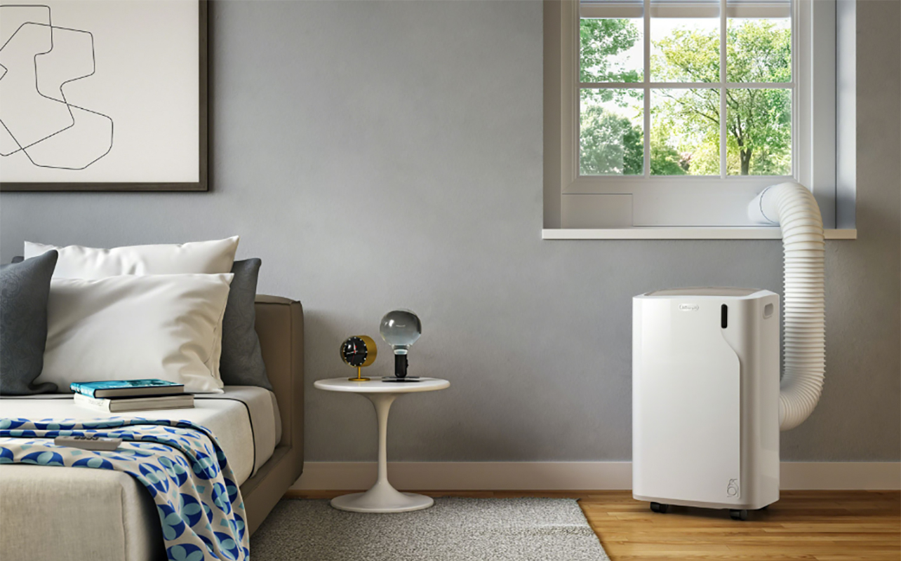 A De'Longhi portable air conditioner being vented out of a window in a bedroom - Leaking Air Conditioner
