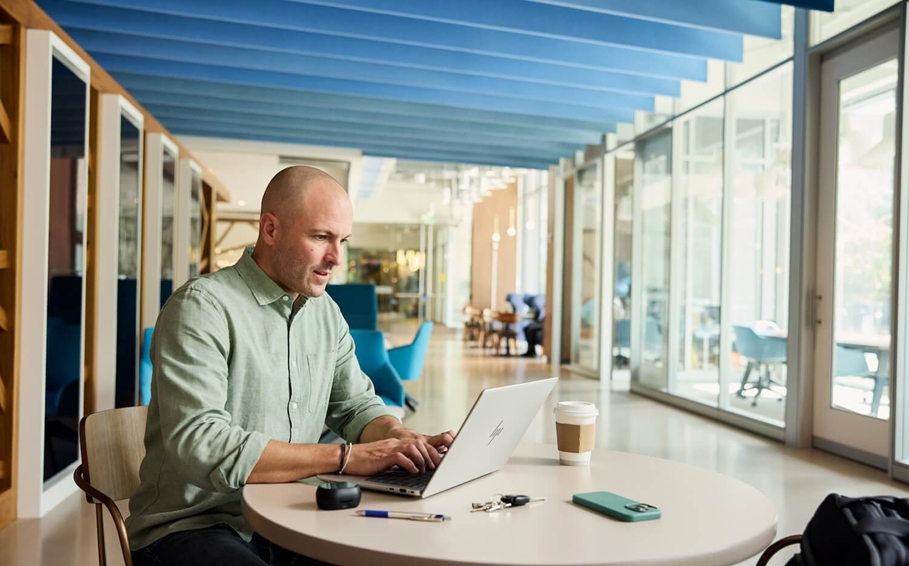 Man sitting at a desk working on an HP Elitebook X laptop.