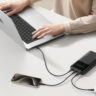 Hands on a laptop being charged with the INIU 27,000mAh power bank.