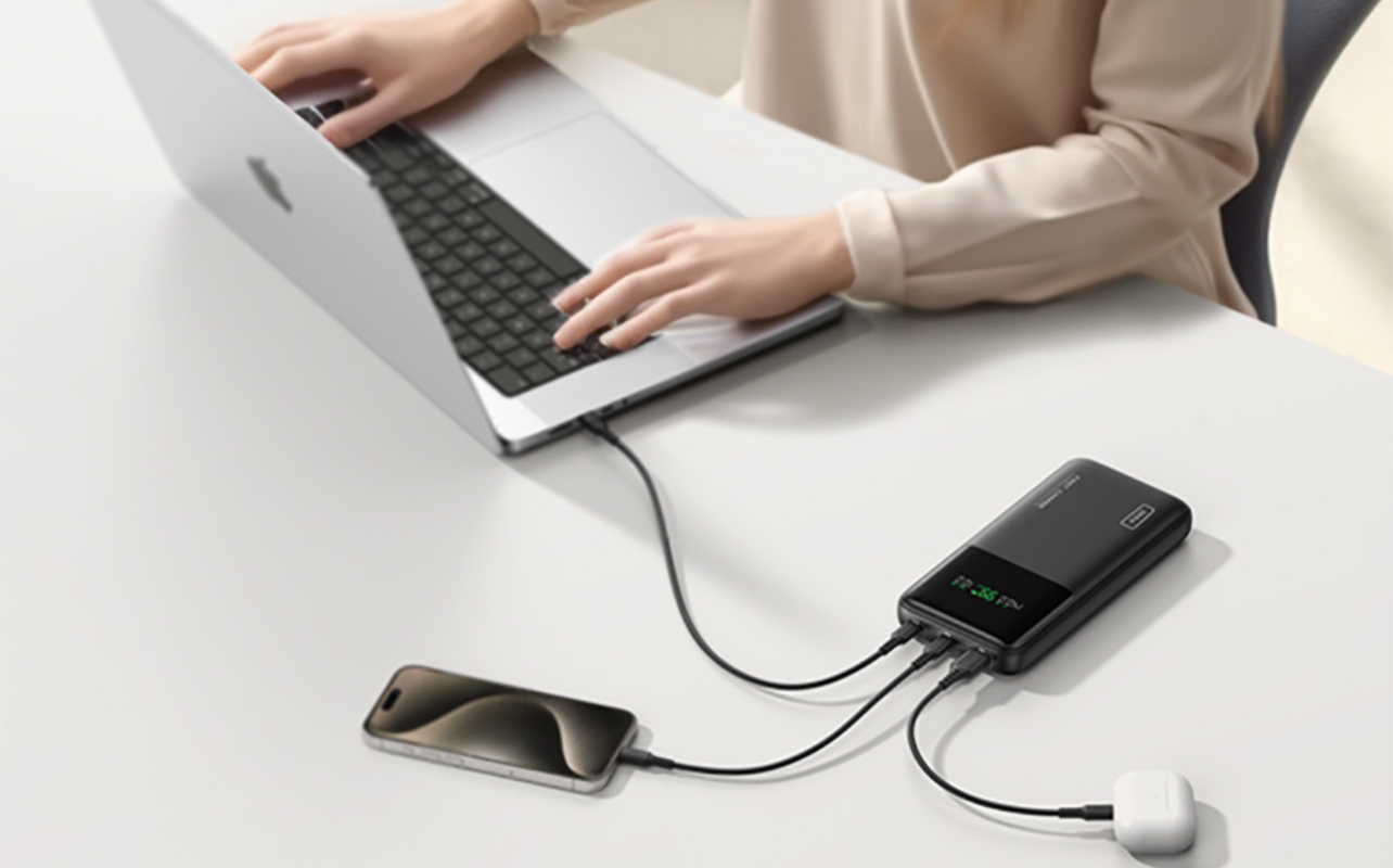 Hands on a laptop being charged with the INIU 27,000mAh power bank.