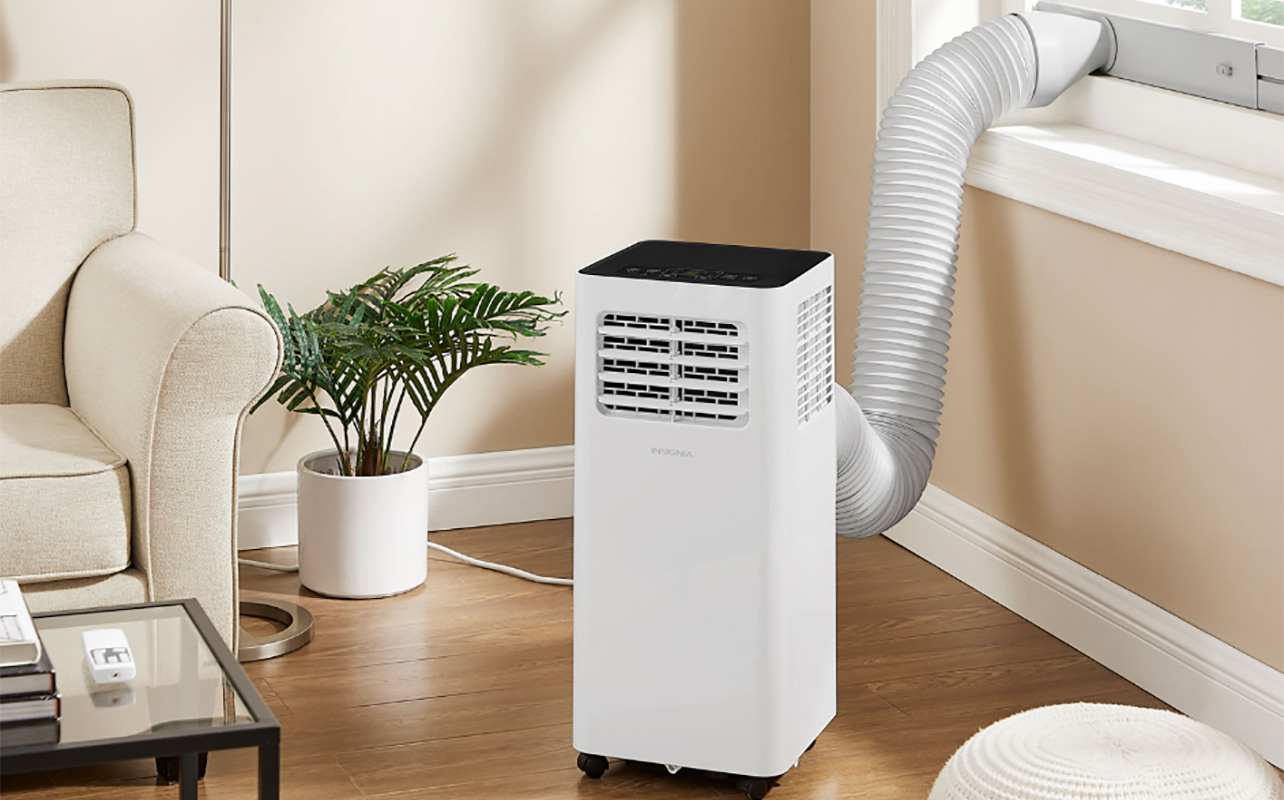 An Insignia portable air conditioner by the window in a living room.