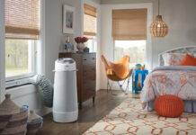 A cylindrical portable air conditioner in a bedroom.