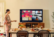 A woman standing beside the Samsung The Frame Pro TV mounted on furniture.