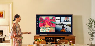A woman standing beside the Samsung The Frame Pro TV mounted on furniture.