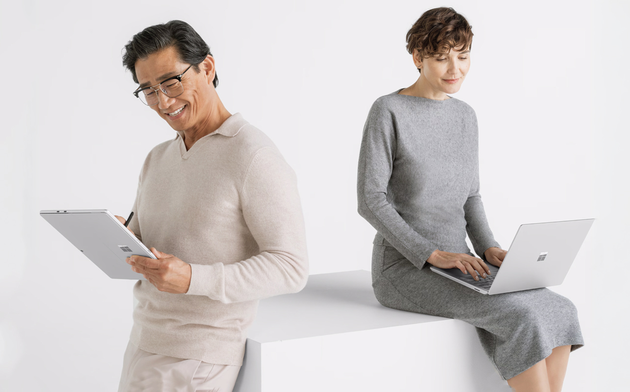 Homme qui utilise un portable 2-en-1 à côté d'une femme qui utilise un portable traditionnel.