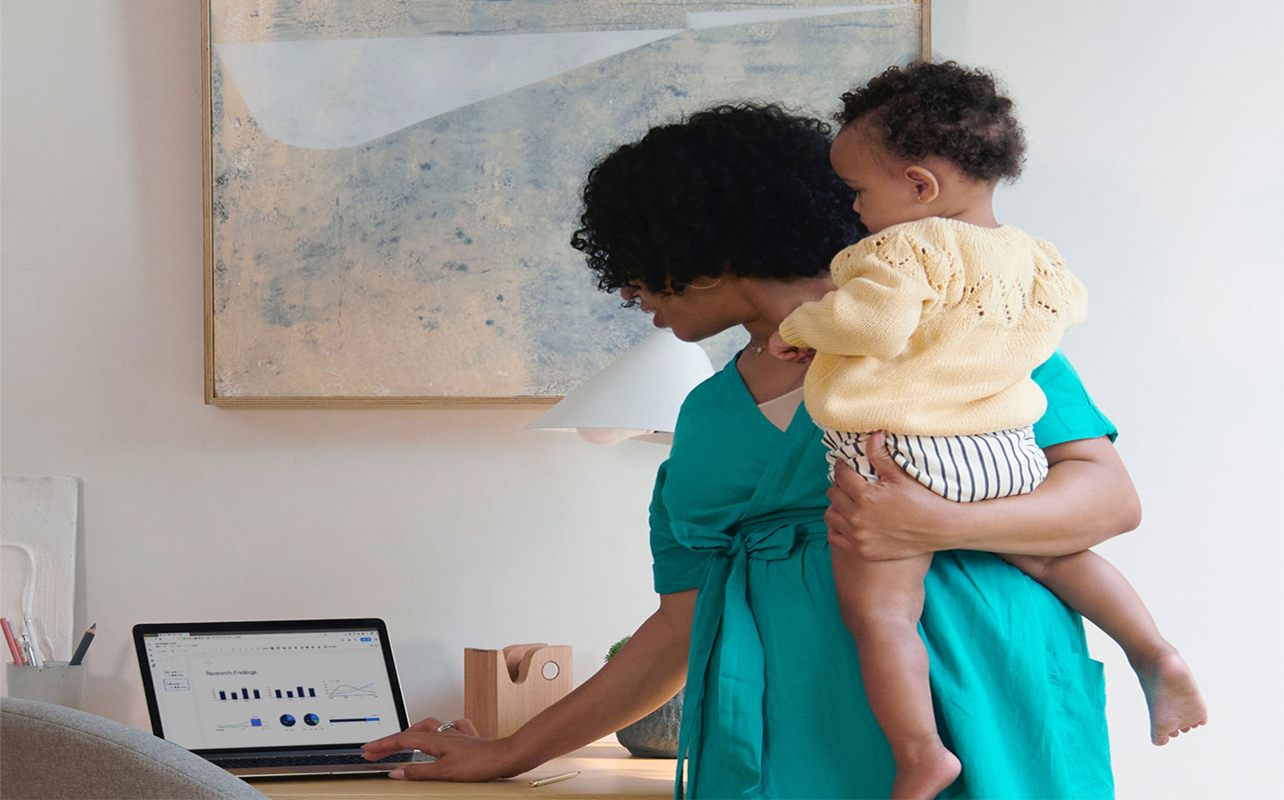 woman carrying a baby while working on laptop on whole home Mesh Wi-Fi system