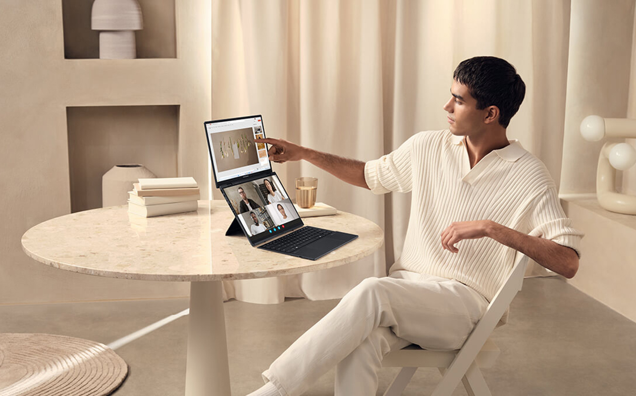 Man using ASUS Zenbook Duo laptop on a table at home.