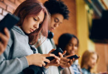 Students using their smartphones in the hallway at school.