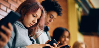 Students using their smartphones in the hallway at school.