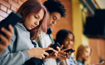 Students using their smartphones in the hallway at school.