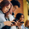 Students using their smartphones in the hallway at school.