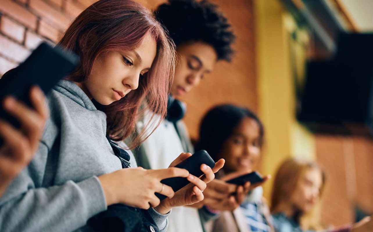 Students using their smartphones in the hallway at school.