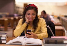 Female student using a smartphone while studying on campus.