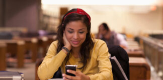 Female student using a smartphone while studying on campus.