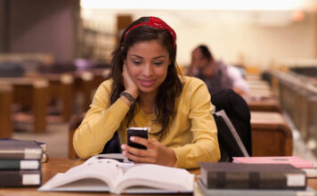 Female student using a smartphone while studying on campus.