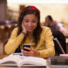 Female student using a smartphone while studying on campus.