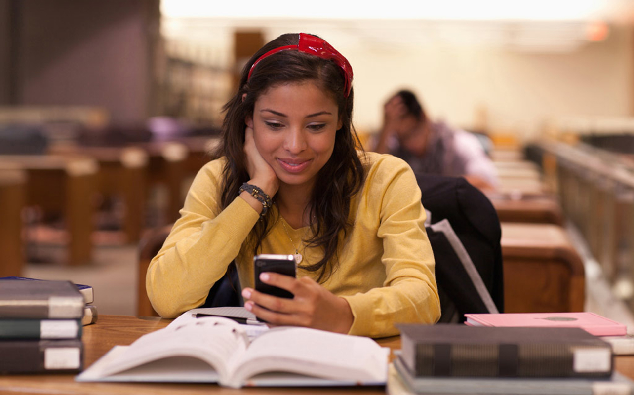 Female student using a smartphone while studying on campus.