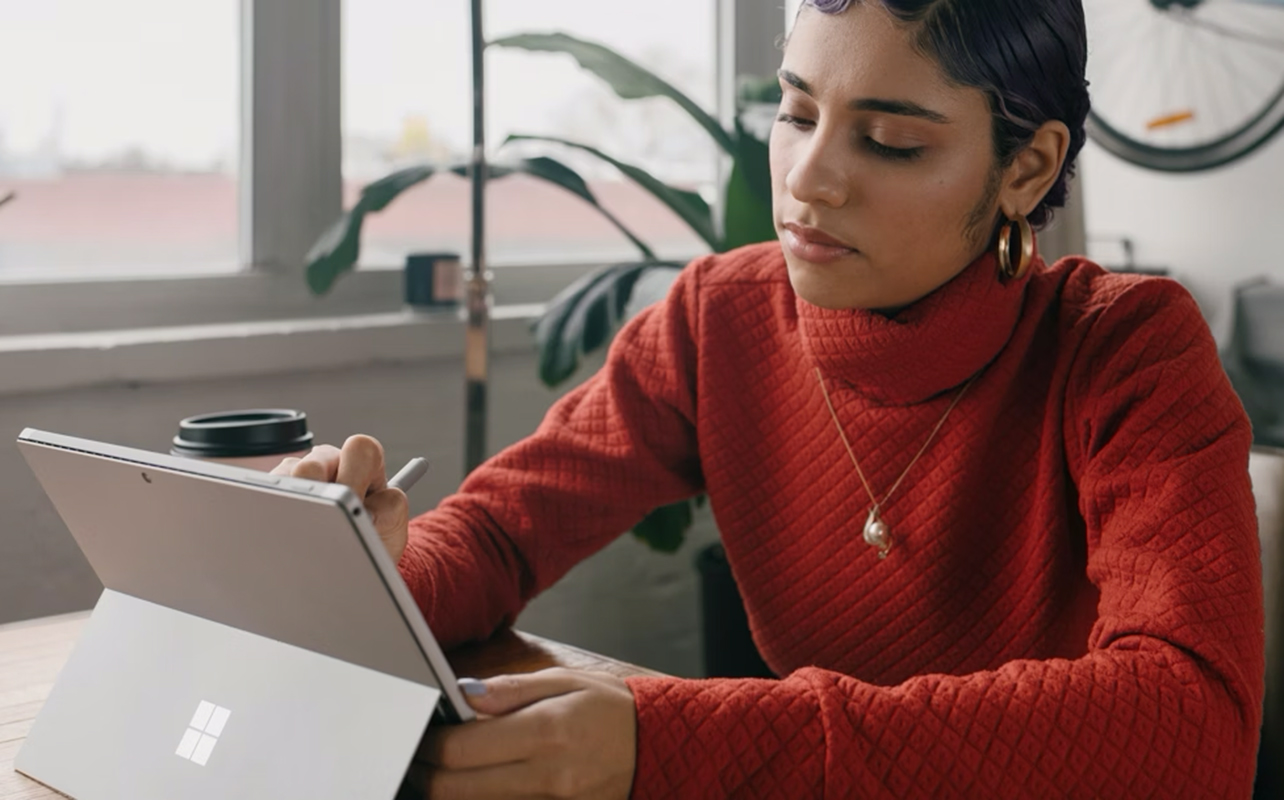 Woman taking a note on a Surface 2-in-1 laptop.