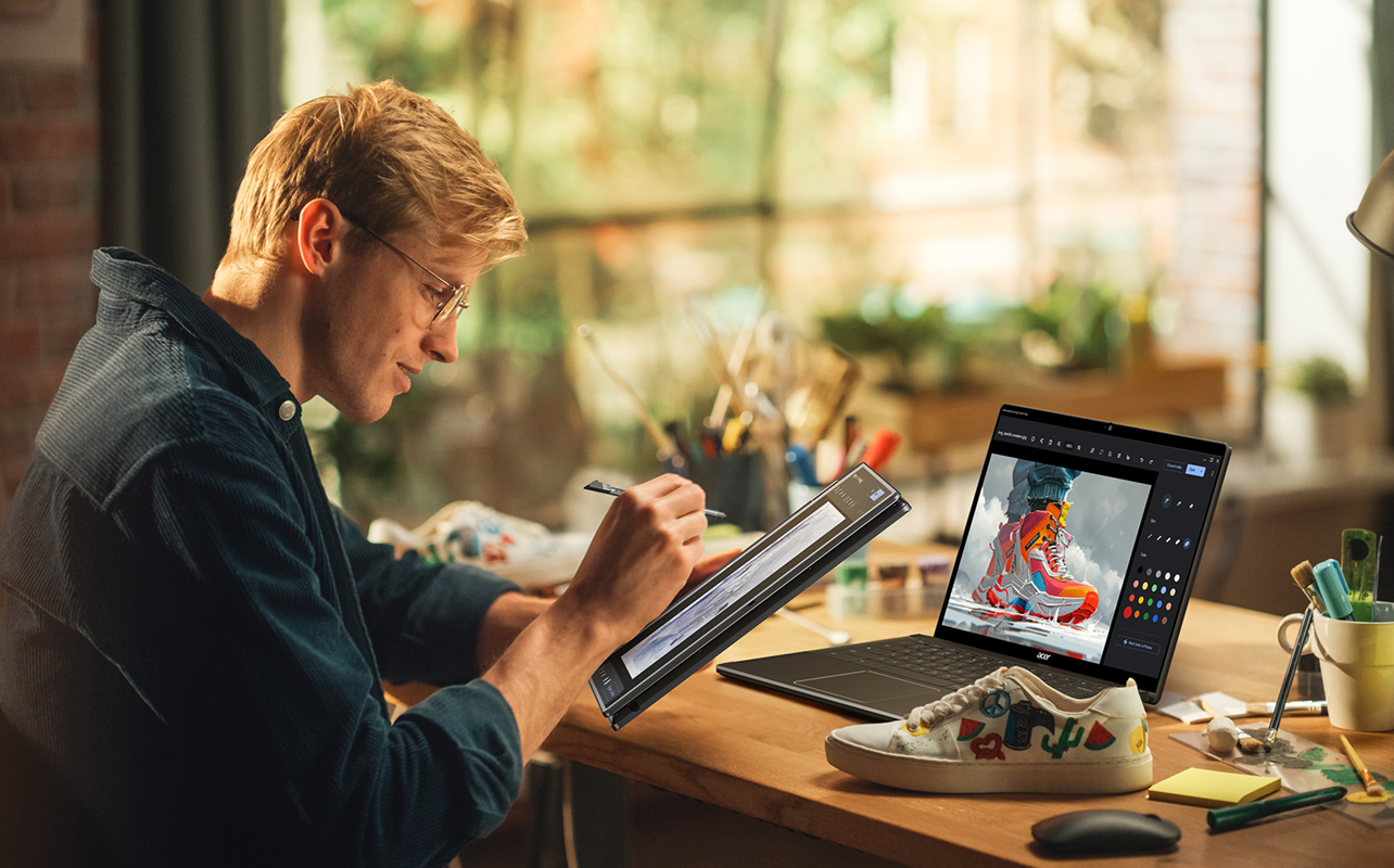 Man taking notes on a 2-in-1 laptop with another laptop nearby.