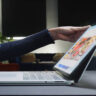 Woman opening Microsoft Surface premium Windows laptop.