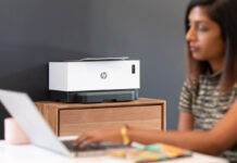 Woman on laptop with HP wireless printer in background.