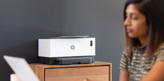 Woman on laptop with HP wireless printer in background.