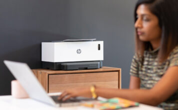 Woman on laptop with HP wireless printer in background.