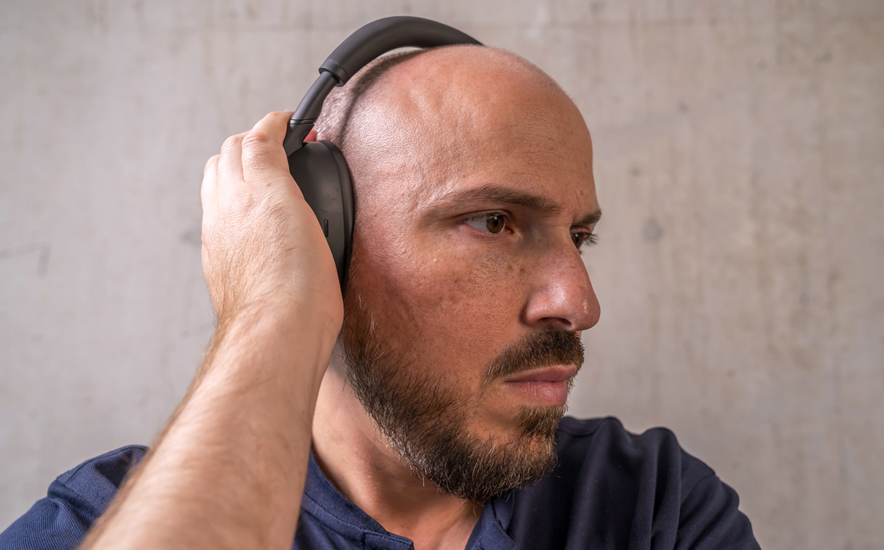 Holding right hand over right ear cup on Sony WH-1000XM6 headphones.