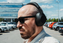 Profile view wearing Sony WH-1000XM6 headphones outdoors in parking lot.