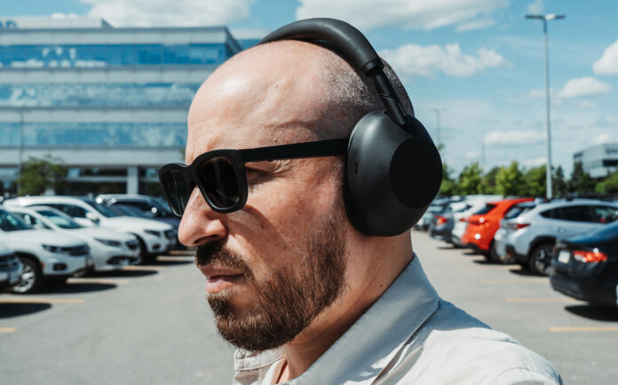 Profile view wearing Sony WH-1000XM6 headphones outdoors in parking lot.