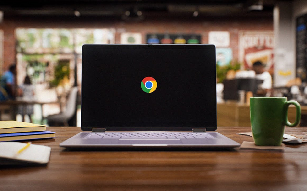 A Chromebook sitting on a desk in a library or cafe.