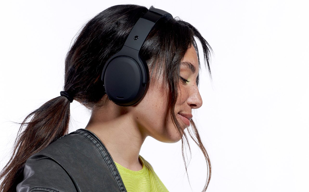 Younger girl wearing over-ear black headphones with eyes closed.