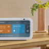 An Amazon Echo Show 5 on a side table showing smart home controls.
