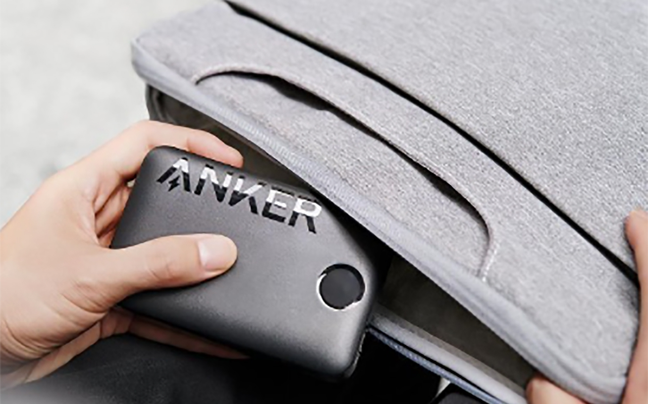 An Anker portable charging bank being put into a bag.