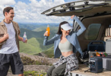 A man and woman sitting on a truckbed with an Anker Solix C300X portable power station