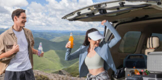 A man and woman sitting on a truckbed with an Anker Solix C300X portable power station
