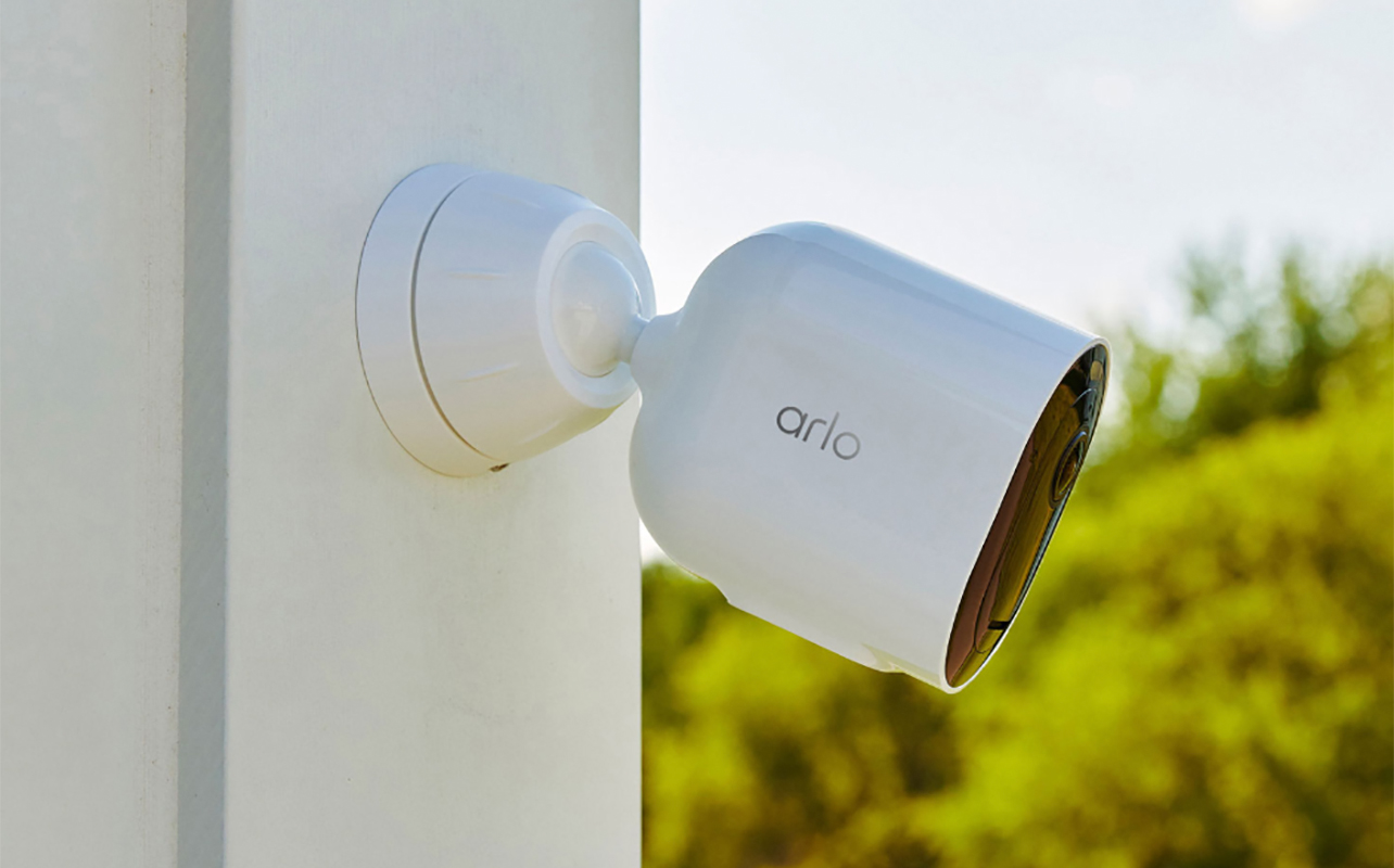 An Arlo outdoor camera mounted on the side of a house.