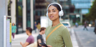 Young female student wearing white JBL headphones on campus.
